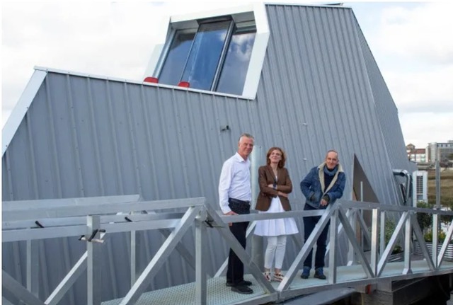 Howard and Sarah with Kevin McCloud standing astride the floating house