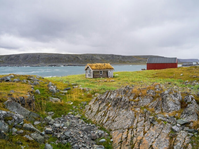 A tiny house with a turf roof on a craggy island