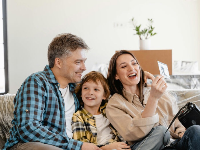 Couple on sofa looking at photo with a child