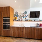 A modern kitchen with walnut panels and plates hanging on the wall