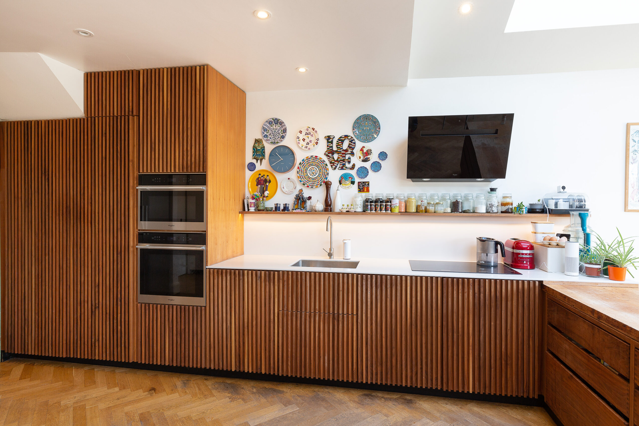 A modern kitchen with walnut panels and plates hanging on the wall